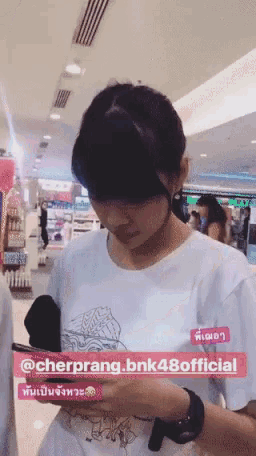 a person in a white shirt is looking at a cell phone