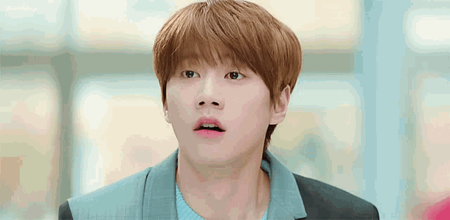 a young man with a surprised look on his face is wearing a blue jacket and sweater .