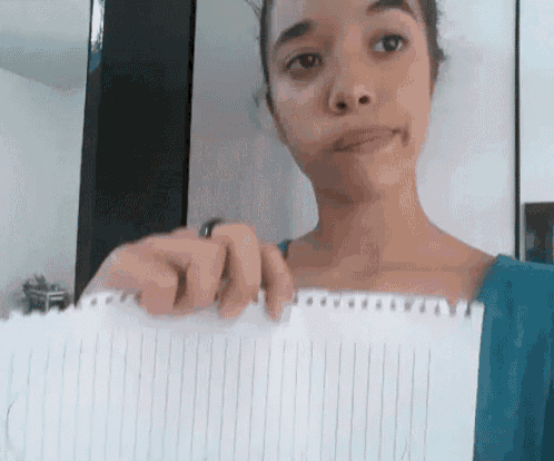 a woman is holding a piece of lined paper and making a face