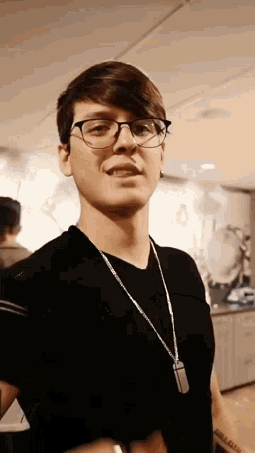 a young man wearing glasses and a black shirt has a tattoo on his arm that says ' i love you '