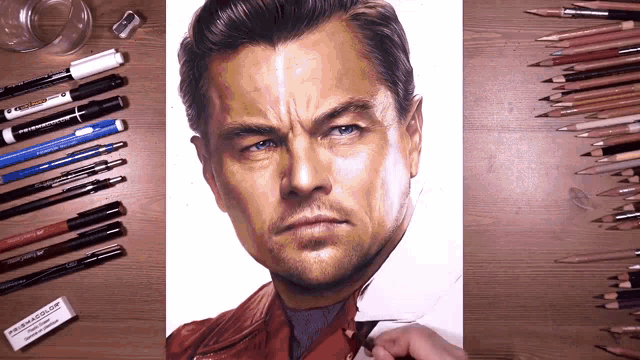 a drawing of leonardo dicaprio is on a wooden table surrounded by pencils and pens