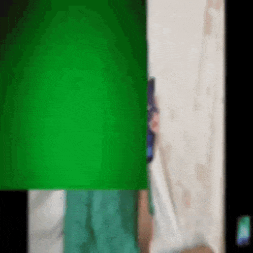a person holding a cell phone behind a green screen .