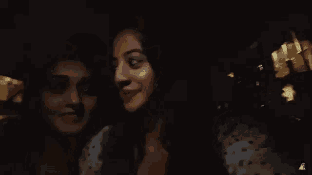 two women are posing for a picture in the dark and smiling .