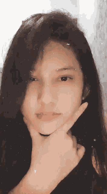 a girl with long black hair is making a funny face with her hand on her chin