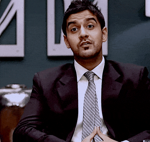 a man in a suit and tie is sitting in front of a sign that says ' a ' on it