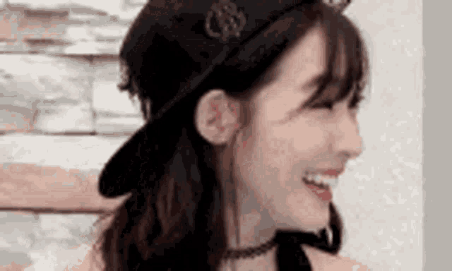 a close up of a woman wearing a hat and choker smiling .