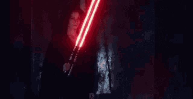 a person is holding two red lightsabers in their hands .