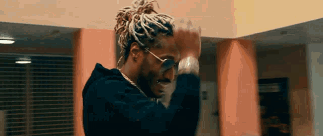 a man with dreadlocks wearing sunglasses and a black hoodie
