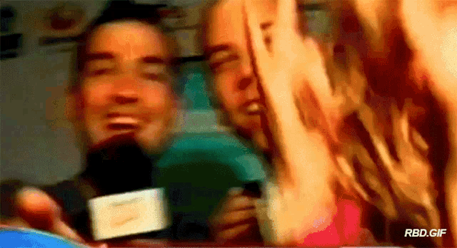 a man is holding a microphone in front of a group of people and the words rbd.gif are on the bottom right