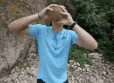 a man in a blue adidas shirt is holding a ball in his hands .