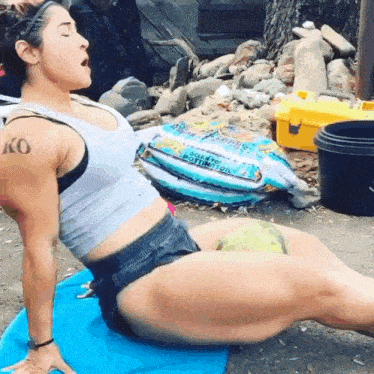 a woman with a tattoo on her arm is stretching on a blue mat