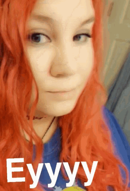 a woman with red hair is wearing a blue shirt with the word eyyy on it