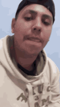 a man wearing a hat and a white hoodie with the word abercrombie on it