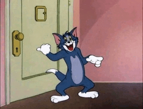 tom from the cartoon tom and jerry is standing in front of a door in a room .