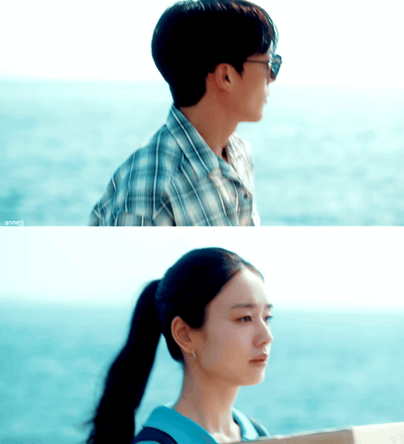 a man in a plaid shirt and a woman in a ponytail are looking out over the ocean
