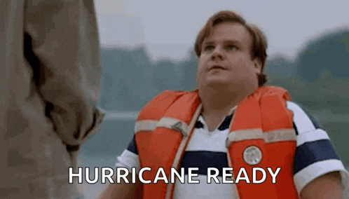 a man wearing a life jacket is ready for a hurricane and talking to another man .