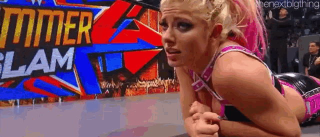 a female wrestler is laying on the ground in front of a sign that says summerslam .