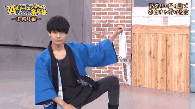 a man wearing a blue kimono is kneeling down