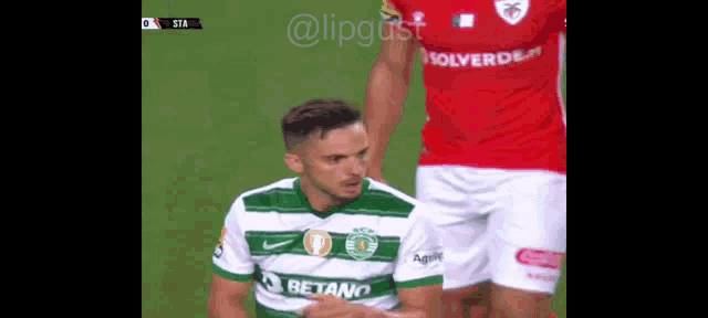 a soccer player wearing a betano jersey is kneeling down on the field