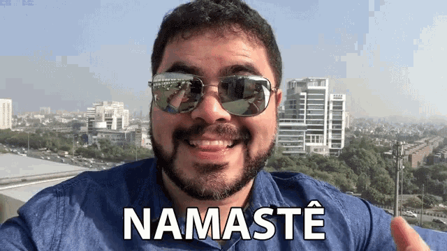 a man wearing sunglasses says namaste in front of a city skyline