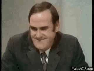a man in a suit and tie is making a funny face and smiling .