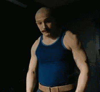 a man in a blue tank top is holding his hands out