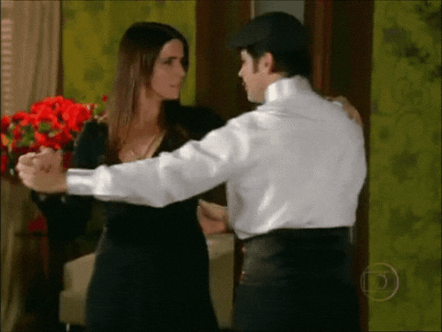 a woman in a black dress is dancing with a man in a white shirt ..