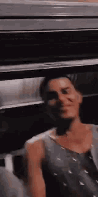 a man in a tank top is standing in a dark room .