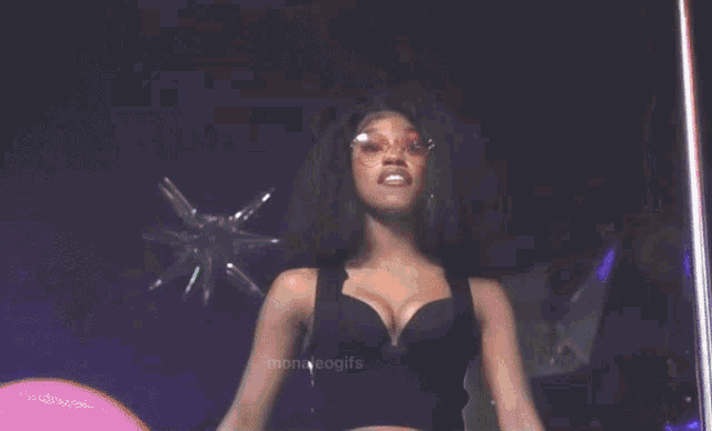 a woman with long nails and sunglasses is dancing on a pole in a club .