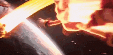 a close up of a person holding a sword with fire coming out of it in a dark room .
