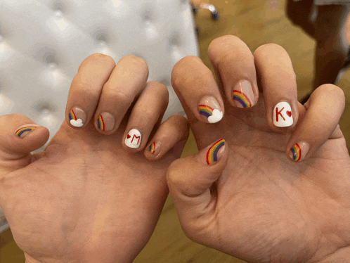 a person 's nails are decorated with rainbows and the letter k on the ring finger