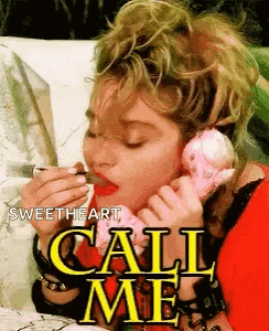 a woman is eating a donut while talking on a pink telephone .