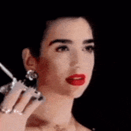 a close up of a woman 's face with red lips and earrings holding a cell phone .