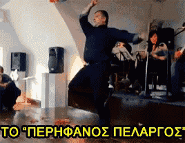 a man in a black shirt is dancing on a stage in front of a sign that says to " perhfanos pelargos "