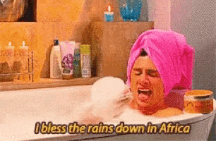 a woman in a bathtub with a pink towel wrapped around her head says i bless the rains down in africa .