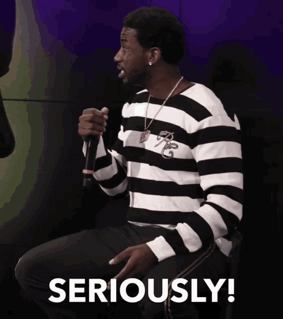 a man in a black and white striped shirt is holding a microphone and the word seriously is below him
