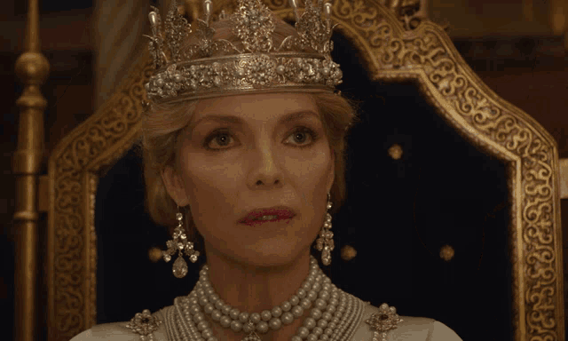 a woman wearing a crown and pearls is sitting on a throne and says " what an "