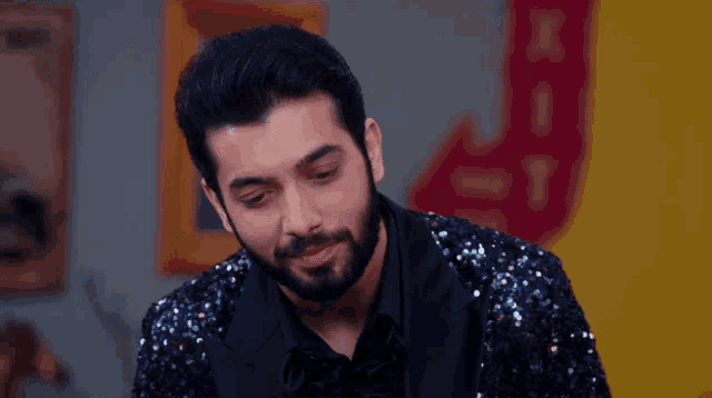 a man with a beard wears a sequined jacket