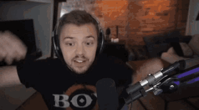 a man wearing headphones and a shirt that says bo 's is standing in front of a microphone .