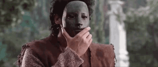 a man is wearing a mask on his face and covering his mouth .