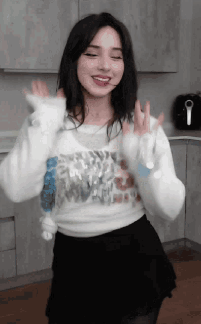 a woman wearing a white sweater and black skirt is dancing