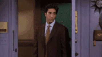 a man in a suit and tie is standing in a doorway with his arms outstretched .