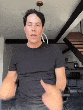 a man in a black shirt is giving a thumbs up sign