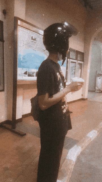 a person wearing a helmet and a mask holds a cup of coffee
