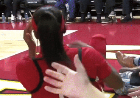 a woman wearing headphones is being touched by a man 's hand on a basketball court