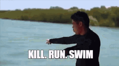 a man is standing in front of a body of water with the words `` kill run swim '' written on the screen .