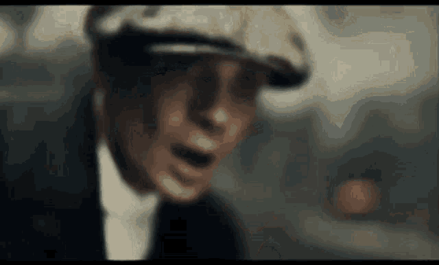 a close up of a man wearing a hat and suit .