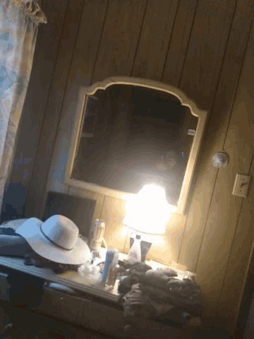 a room with a mirror a lamp and a hat on a table