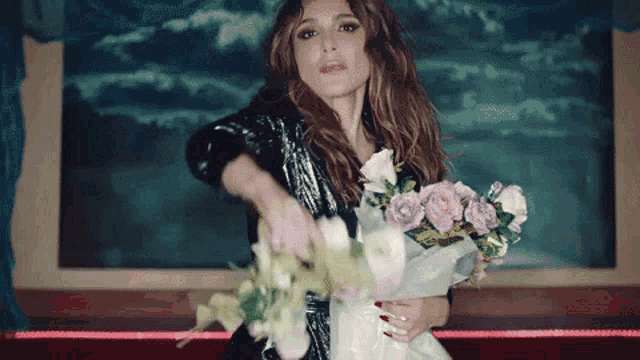 a woman in a black jacket is holding a bouquet of flowers in her hands .