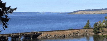 a train bridge over a body of water with a bridge in the background